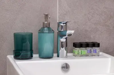 a bathroom sink with a soap dispenser and a bottle at City Hall Suites in Limassol