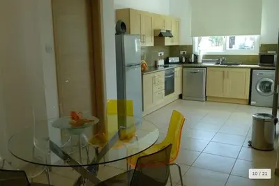 a kitchen with a glass table and yellow chairs at Oresti Villa with a pool in Paralimni