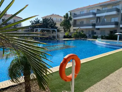 a swimming pool with an orange life preserver next to a building at Mythical Sands Resort, Protaras, Choose Joy Apt in Paralimni