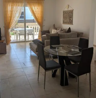 a living room with a couch and a table and chairs at St Andrews Apartment in Xylophaghou