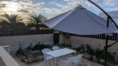 a white table and chairs and an umbrella at St Andrews Apartment in Xylophaghou