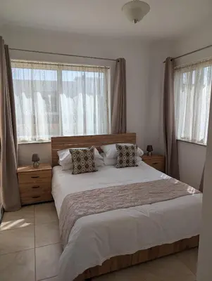 a bedroom with a large bed with two windows at St Andrews Apartment in Xylophaghou