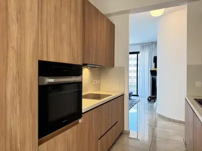 a kitchen with wooden cabinets and a black oven at Wealthystays Premium Residence in Nicosia