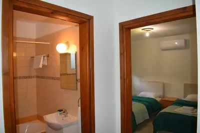 a bathroom with a sink and a toilet and a bed at Trinity Blue Apt in Paralimni