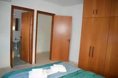 a bedroom with a bed and a bathroom with a mirror at Trinity Blue Apt in Paralimni