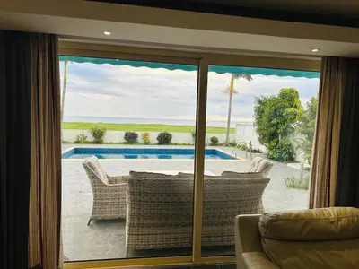 a living room with a sliding glass door looking out at a pool at Villa Eva in Mazotos