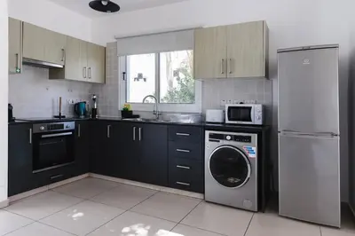 a kitchen with black cabinets and a washer and dryer at Nissini Villas in Ayia Napa