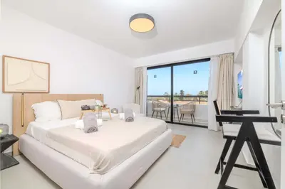 a white bedroom with a bed and a desk at Finikoudes Marina View 202 in Larnaka