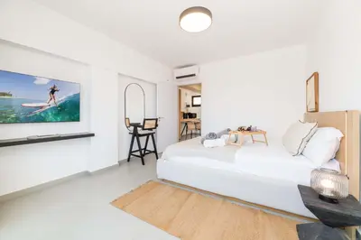 a white bedroom with a bed and a tv at Finikoudes Marina View 202 in Larnaka
