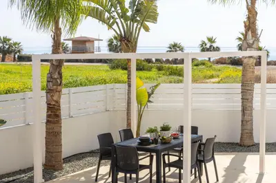 a patio with a table and chairs and palm trees at Sweet Seaview Villa in Ayia Napa