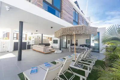 a patio with white chairs and an umbrella at Protaras Aqua Pearl Villa AQ18 in Protaras