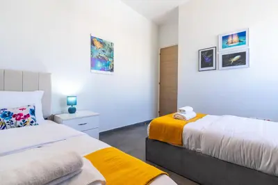 two beds in a bedroom with white walls at Snobby 2-Bedroom Apartment in Larnaka