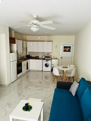 a living room with a blue couch and a kitchen at Sofia`s place in Voroklini