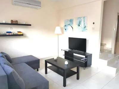 a living room with a blue couch and a tv at Ionian Breeze Family House Walk to Beach And Dining in Paralimni