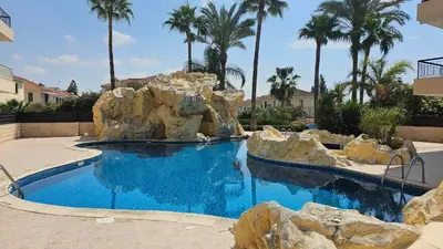 a swimming pool with rocks in a resort at Mediterranean Sunrise Apartments A2 in Voroklini