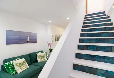 a living room with a green couch and stairs with a lighthouse at Beach Walk - Central, Cool, Cute, Convenient in Limassol