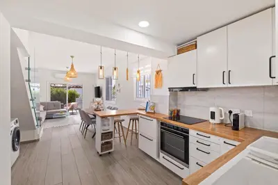 a kitchen with white cabinets and a dining room at Endless Summer Beach House in Pervolia