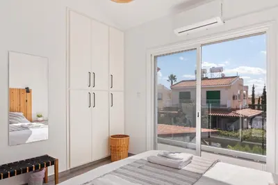 a white bedroom with a large window and a bed at Endless Summer Beach House in Pervolia