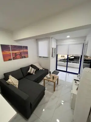 a living room with a black couch and a table at Mandy's apartment in Larnaka