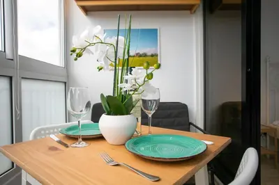 a table with plates and glasses and a vase with flowers at Palmove Makenzy Ria Studio in Larnaka