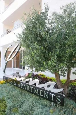 a sign in front of a building with a tree at Corina Suites & Apartments in Limassol