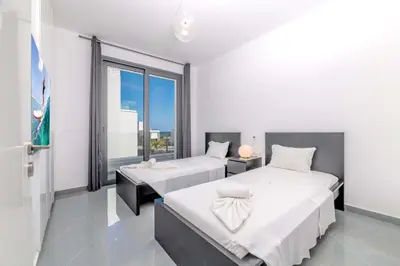 a bedroom with two beds and a large window at By The Beach - Aura Villa in Protaras