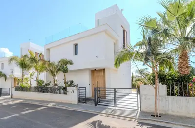 a white house with palm trees in front of it at By The Beach - Aura Villa in Protaras