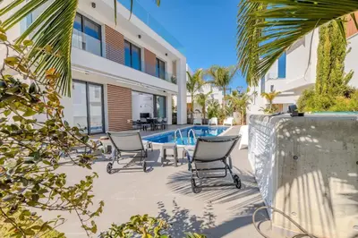a patio with chairs next to a swimming pool at By The Beach - Aura Villa in Protaras