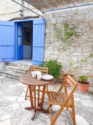 a wooden table and chairs on a patio with a blue door at Cozy Courtyard Apartment in Skarinou