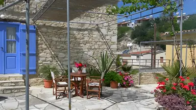 a patio with a table and chairs and flowers at Cozy Courtyard Apartment in Skarinou
