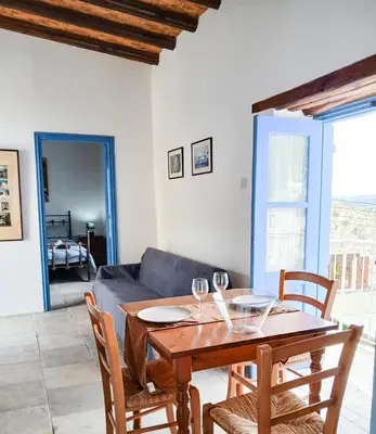 a dining room with a table and chairs and a couch at Cozy Courtyard Apartment in Skarinou