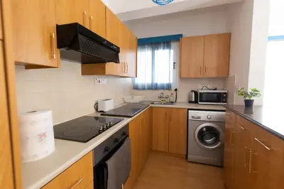a kitchen with wooden cabinets and a washer and dryer at Downtown apartment - Ayia Napa in Ayia Napa