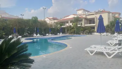 a swimming pool with chairs and umbrellas in a resort at Pyla Gardens A104 in Pyla