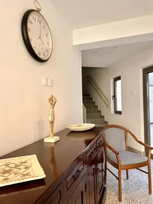 a room with a clock on the wall and a table at 9 Muses Holiday apartments in Larnaka
