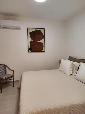a bedroom with a white bed and a chair at 9 Muses Holiday apartments in Larnaka
