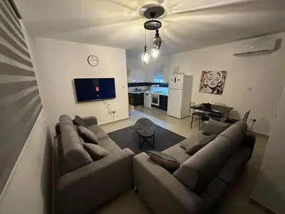 a living room with a large couch and a kitchen at 5 minutes to the sea in Kyrenia new port in Meniko