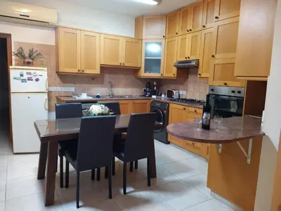 a kitchen with wooden cabinets and a table and chairs at The Tower Penthouse in Strovolos