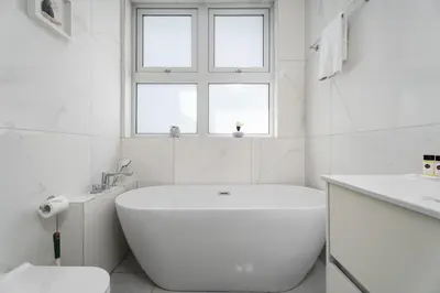 a white bathroom with a tub and a window at Levanda Hills Escape in Protaras in Paralimni