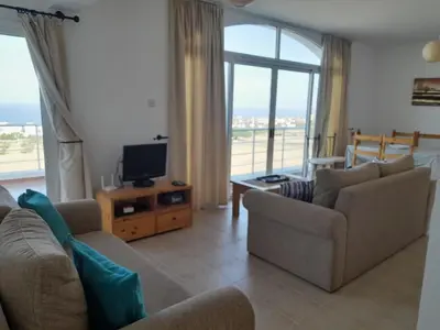a living room with two couches and a tv and a balcony at Crystal Bay Marina B3-5 in Troulli