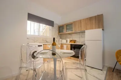 a kitchen with a table and chairs and a white refrigerator at Modern 2BR Steps from Beach in Voroklini