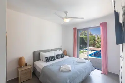 a bedroom with a bed and a window with a pool at Ayia Napa Satin Villa SVI1 in Ayia Napa