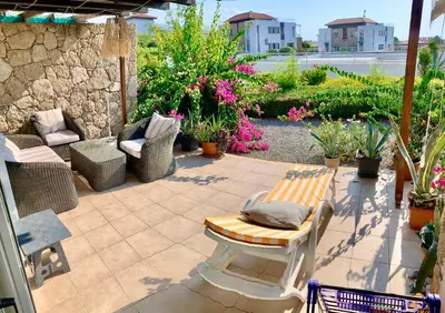 a patio with a bench and chairs and flowers at Boho Beach Apartment in Tatlisu