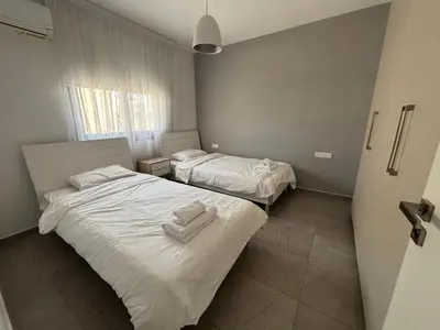 two beds in a room with white sheets and towels at Mordern 2BD APT Perfect for Family or Group in Larnaka