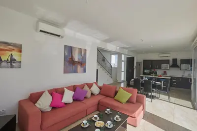 a living room with a red couch with colorful pillows at Pearl Villas in Protaras
