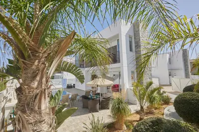 a white house with palm trees in front of it at Pearl Villas in Protaras