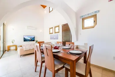 a dining room and living room with a table and chairs at Kymma River Villa #4 in Ayia Napa