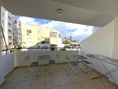 a balcony with chairs and a table on a building at 2 Combined Apts, Fast Wi-Fi, 5 Min Walk to Beach in Larnaka