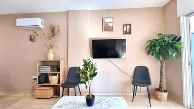 a living room with two chairs and a tv on the wall at 2 Cozy Apts, Fast Internet, 5 Min Walk to Beach! in Larnaka