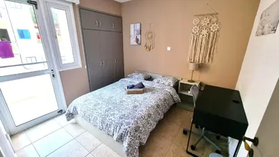 a bedroom with a bed and a desk and a window at Spacious 3Apt Combo, Fast WiFi, 5Min Walk to Beach in Larnaka