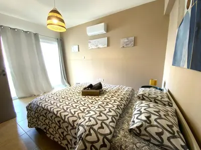 a bedroom with two beds and a large window at Spacious 3Apt Combo, Fast WiFi, 5Min Walk to Beach in Larnaka